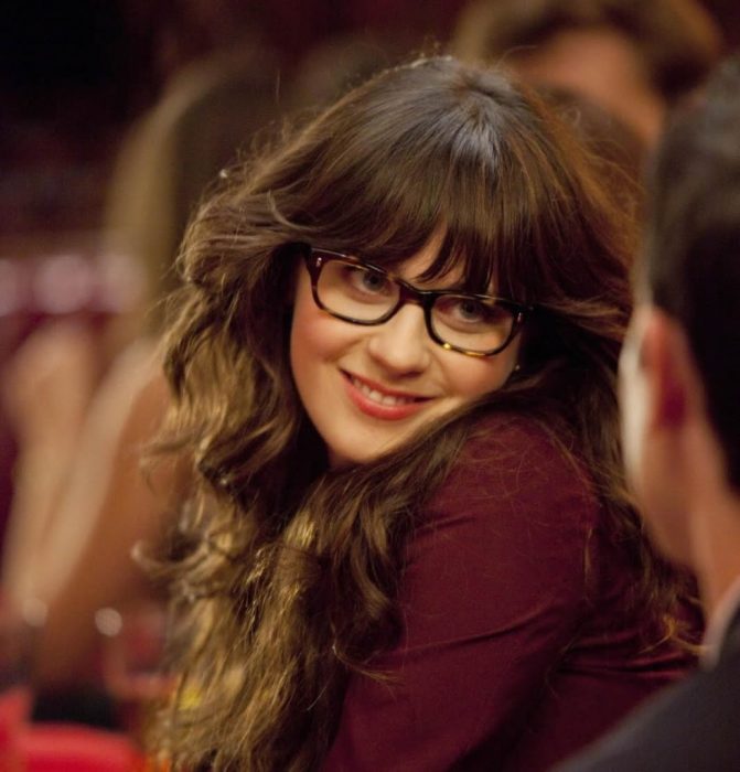 Chica de la serie new girl cenando con un chico y sonriendo 