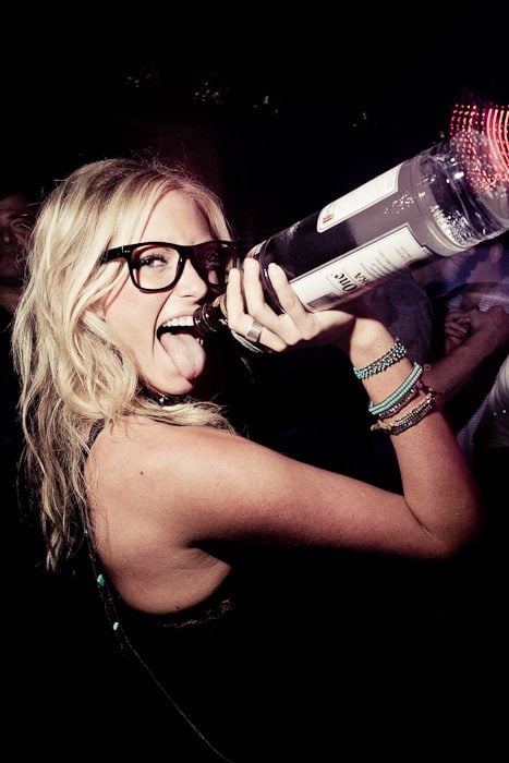 chica sosteniendo una botella en una fiesta 