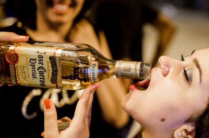 chica tomando tequila directamente de la botella 