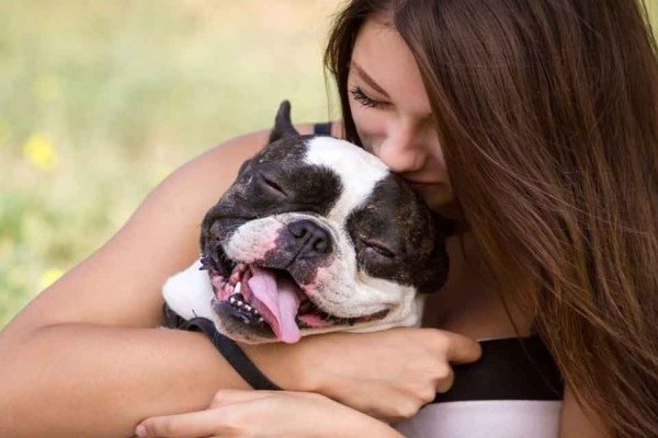 chica abrazando a un perro mientras él sonrie