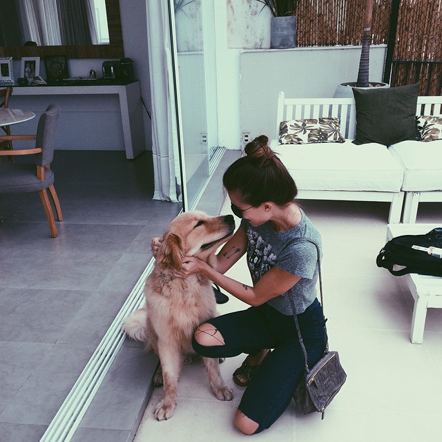 chica acariciando a un perrito en medio de la sala de una casa 