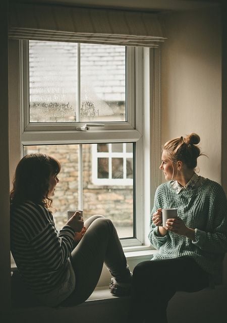 Chicas frente a una ventana conversando 