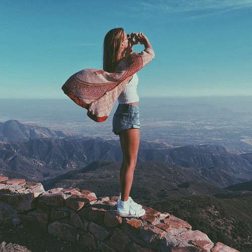 Chica parada sobre una pared de rocas viendo el horizonte 