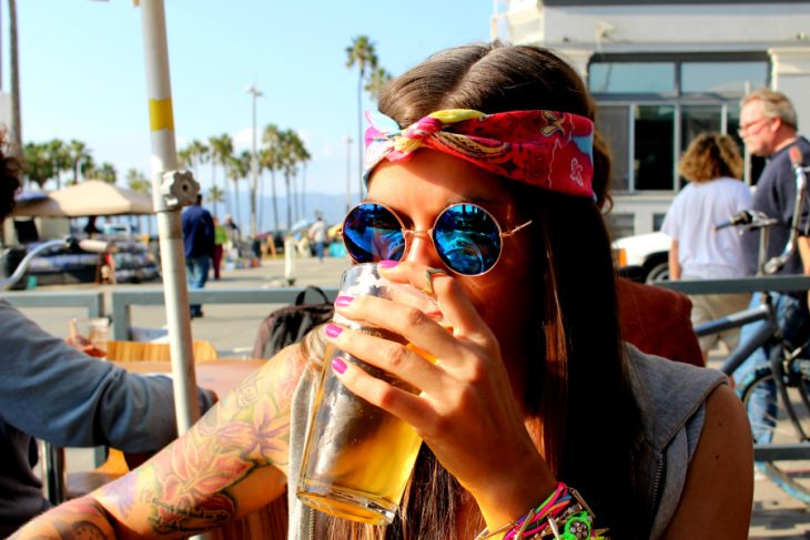 Chica bebiendo cerveza vestida como hippie