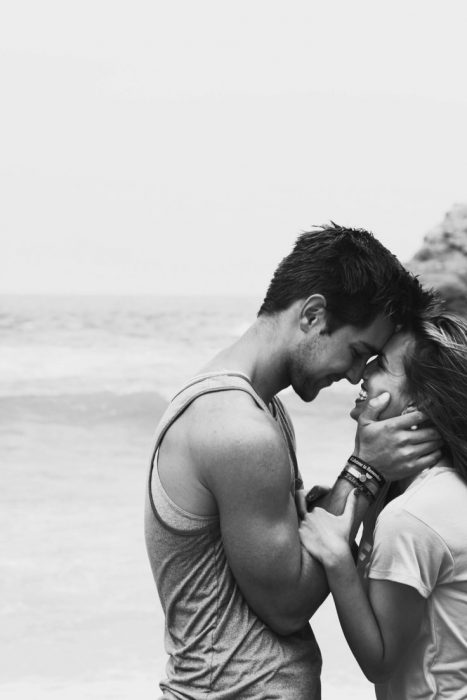 Pareja de novios abrazados viendose de frente parados en una playa