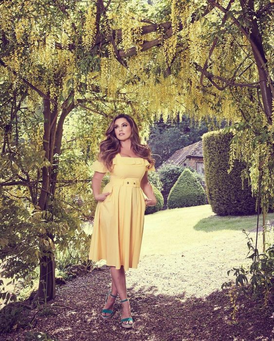 Chica usando un vestido amarillo mientras está en un campo bajo un árbol 