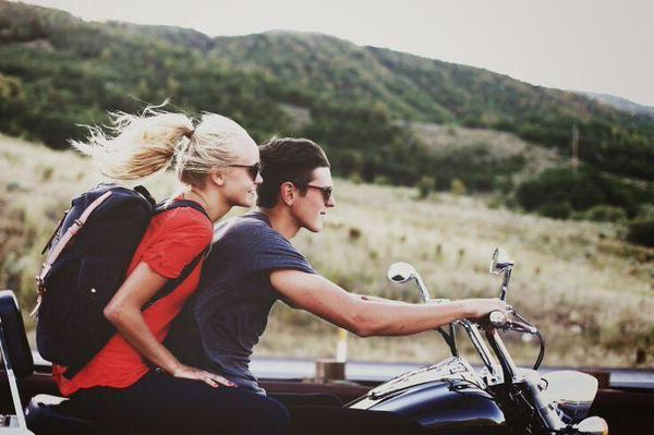 Pareja de novios viajando en una motocicleta por la carretera 