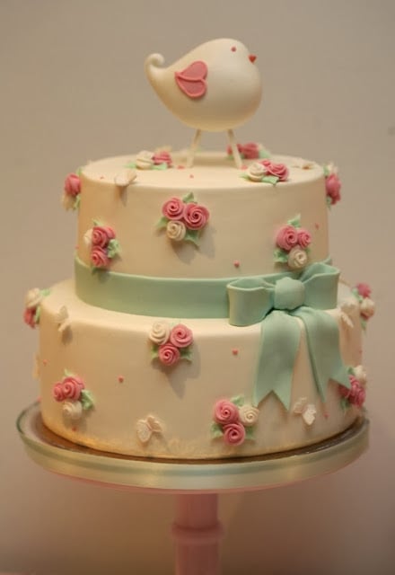 Pastel de baby shower con un pajarito en la cima de la torta 