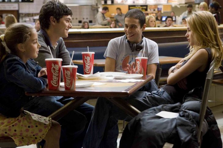 chicos en una mesa con cocas conversando 