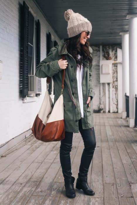 Chica usando un pantalon negro blusa blanca y gabardina verde con una bolsa de mano grande 