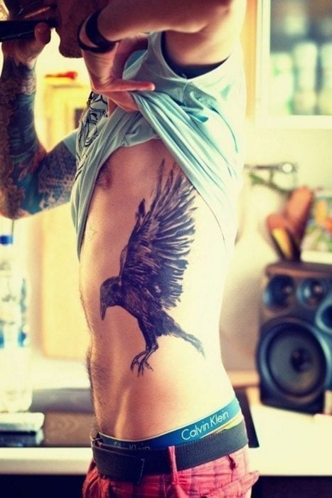 Chico con pájaro tatuado en el costado 