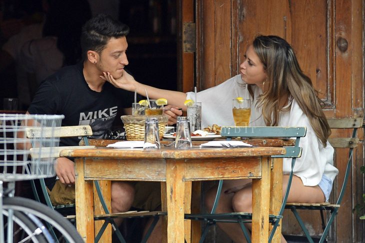 Pareja de novios en un restaurante comiendo y ella acariciándolo 