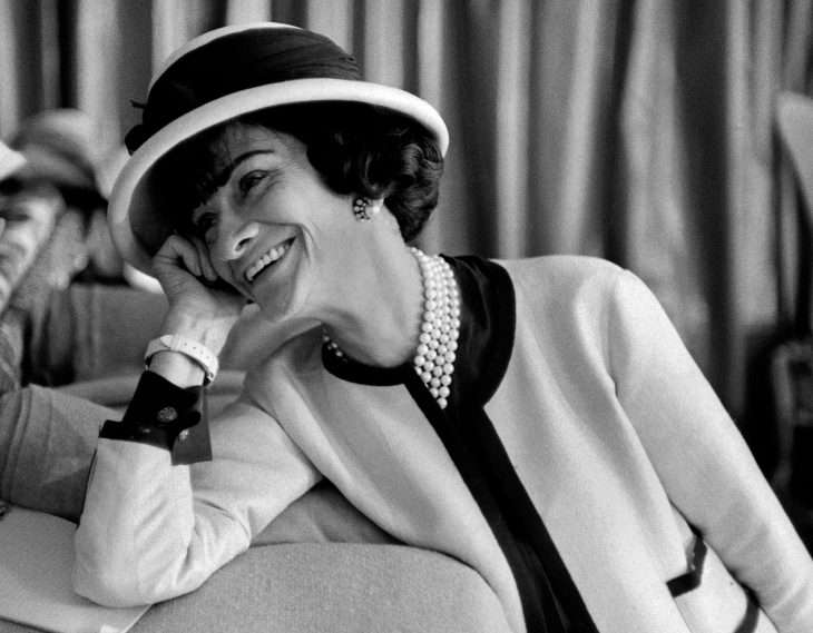 Diseñadora de modas coco chanel usando un traje sastre sombrero y perlas