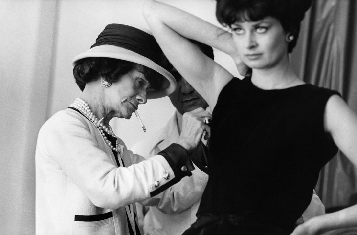 Diseñadora de modas coco chanel arreglando el vestido de una modelo mientras fuma 