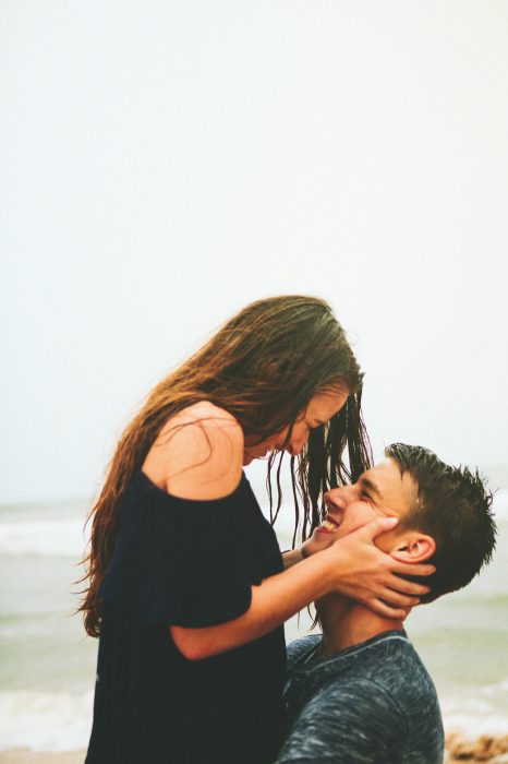 Chico abrazando a una chica mientras están en la playa 