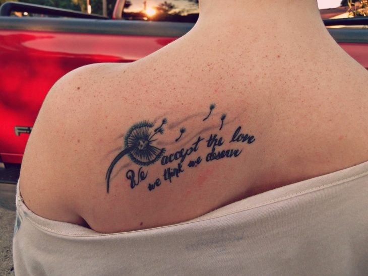 chica mostrando su tatuaje de una frase en la espalda 