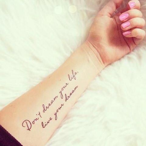 brazo de una chica que esta puesto sobre un cojín mostrando su tatuaje de una frase en ingles 