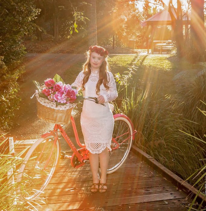 Niña con síndrome de down al lado de una bicicleta 