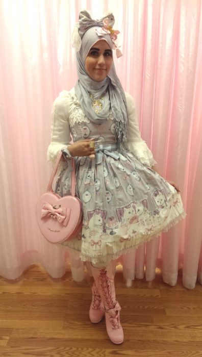 Chica usando un vestido gris con rosa de flores con un bolsa rosa y un hijab de color gris 