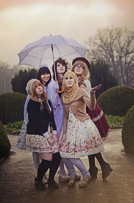 Chicas usando vestidos cortos blancos con flores de colores mientras sostienen un paraguas bajo la lluvia 