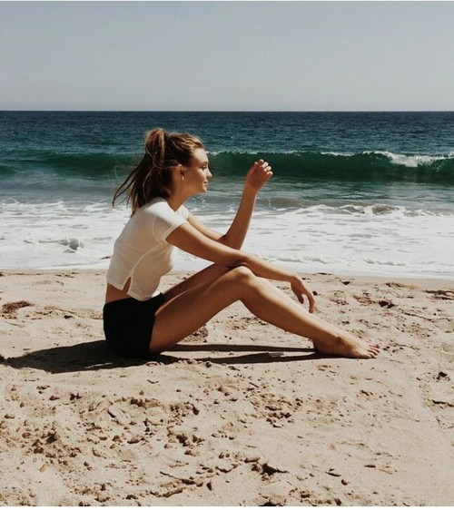 Chica sentada en la playa pensando 