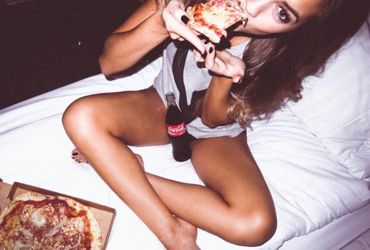 Chica comiendo pizza y tomando coca 