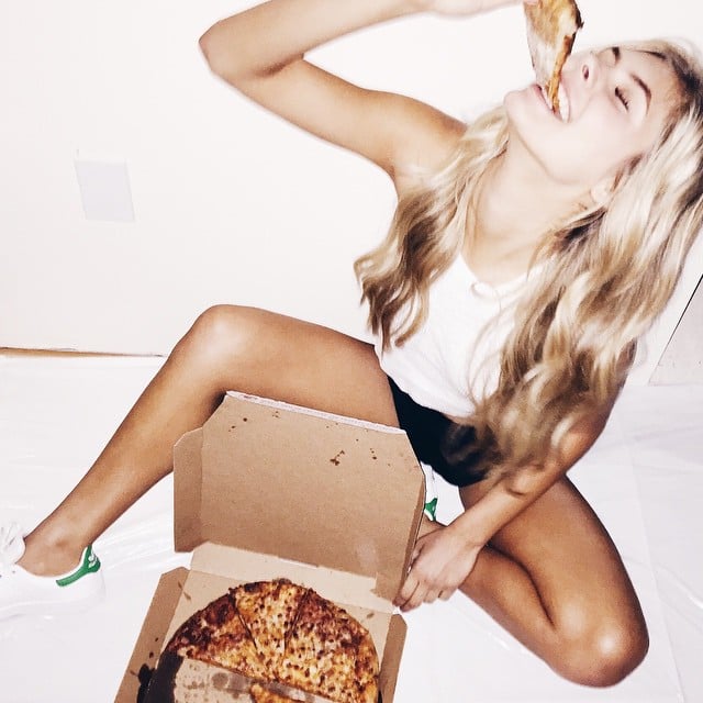 Chica sentada comiendo pizza 