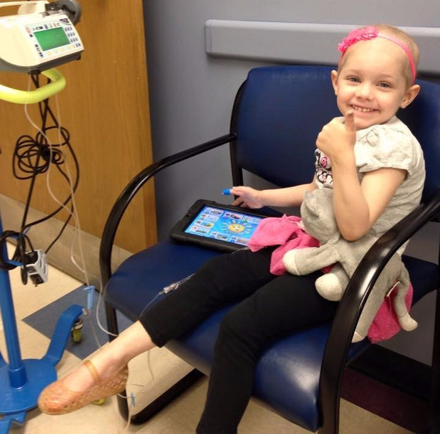Niña enferma de cancer sentada en una silla recibiendo un tratamiento de quimioterapia 