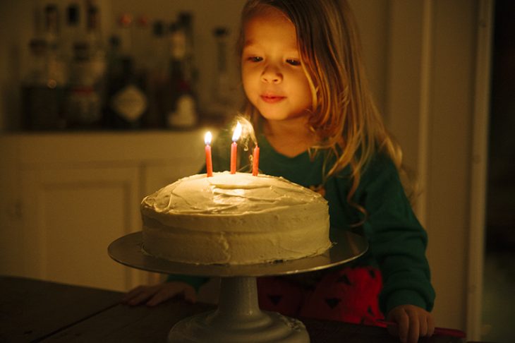 niña apagando velitas de pastel 