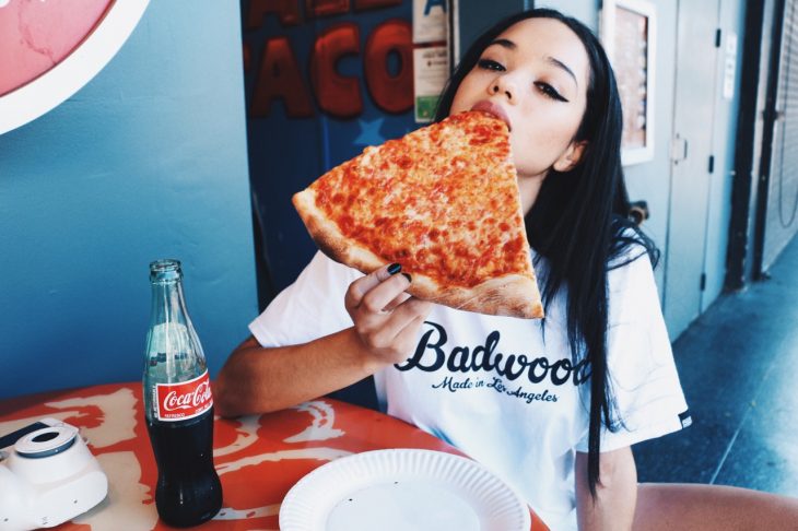 Chica comiendo rebanada de pizza 