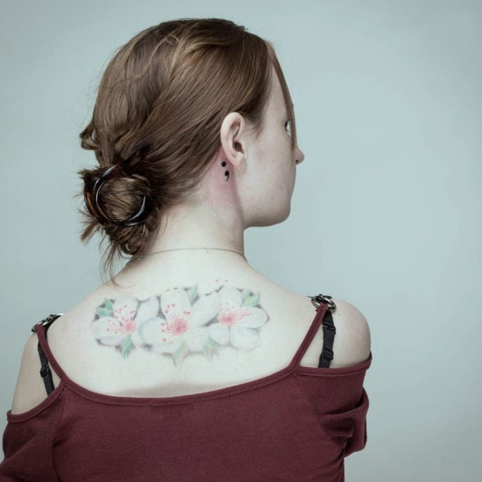 Chica con tatuaje de punto y coma detrás de la oreja 
