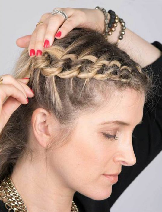 Chica poniéndose pasadores en el cabello después de hacer una trenza 