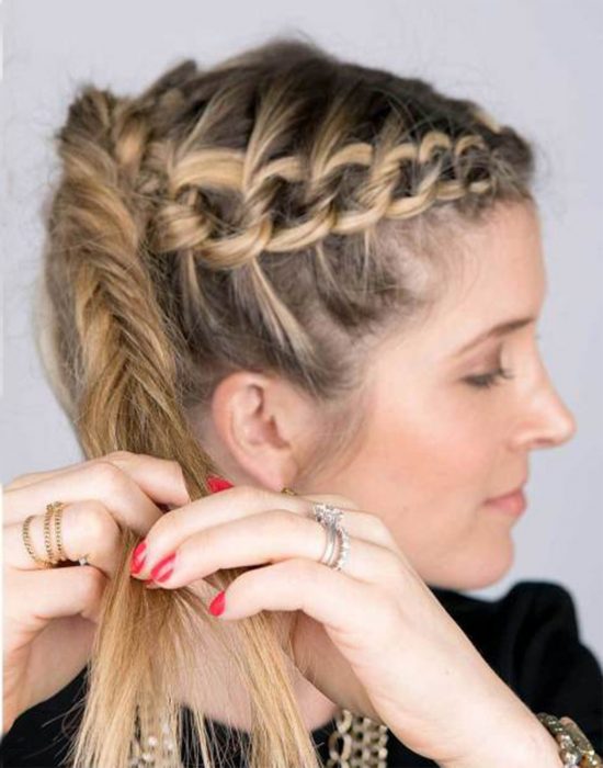 Chica trenzando su cabello en una cola de pez 