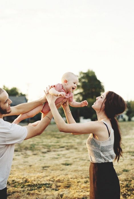 Pareja sosteniendo a un bebé mientras están en un campo 