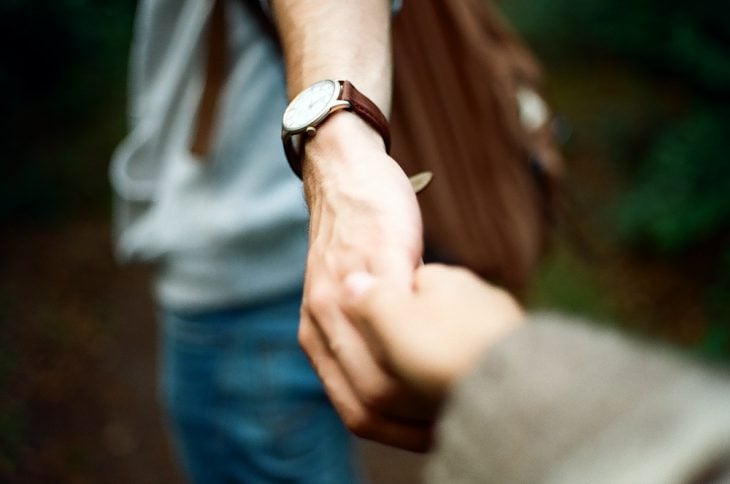 Chico con un reloj tomando de la mano a su novia 