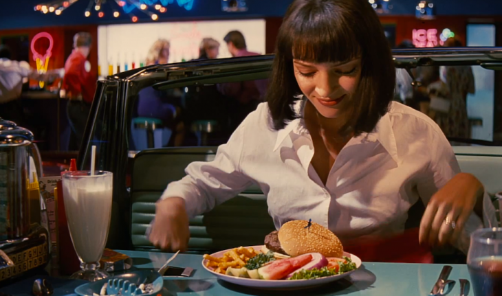 Escena de la película pulp fiction chica sentada comiendo hamburguesa