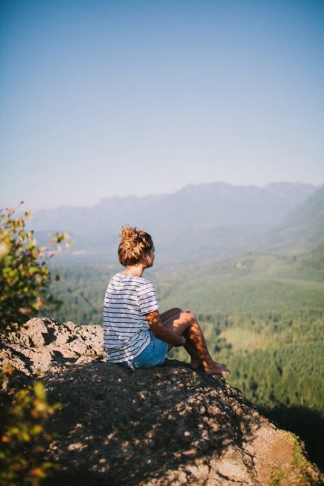 Chica sentada en una roca mirando al horizonte 
