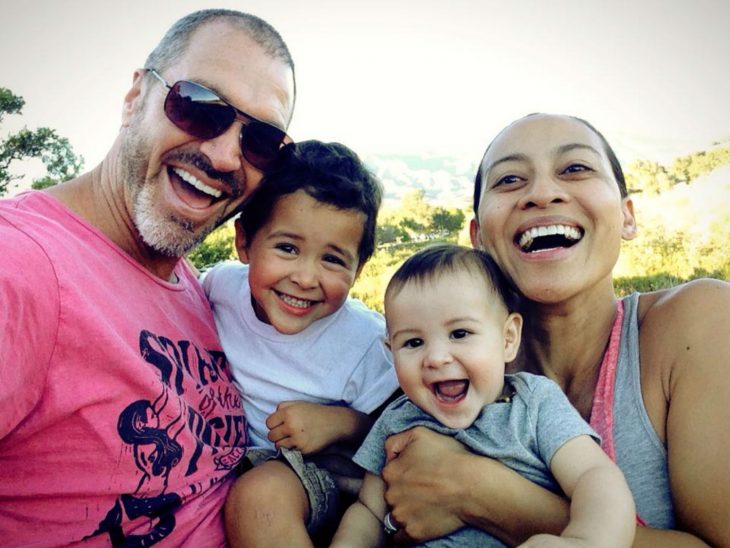 madre y padre sosteniendo a sus hijos mientras están sonriendo 