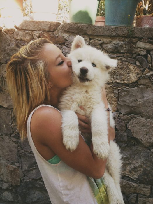 Chica abrazando a un perro Samoyedo 