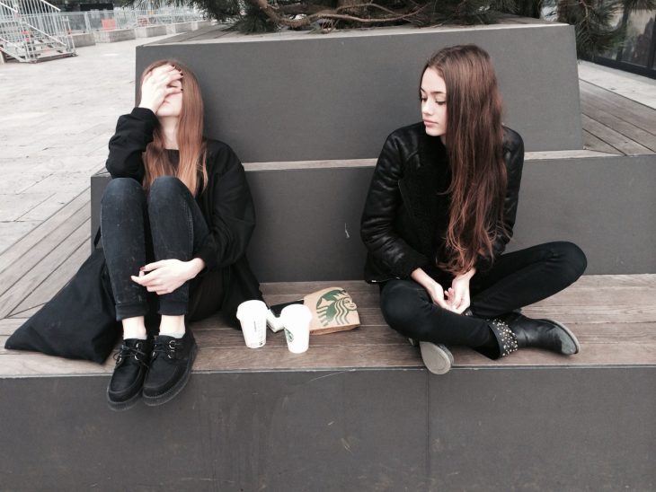 Chicas sentadas en una banca con café de Starbucks 