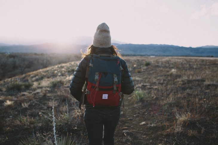 Chica con una mochila observando el paisaje 