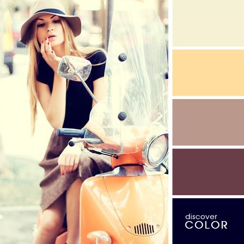Chica en una motocicleta usando una falda de color café con una blusa negra y un sombrero de color café