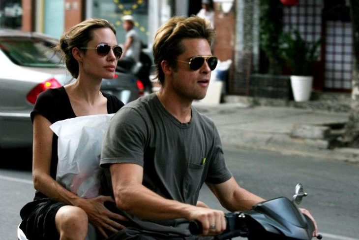 Brad pitt y angelina jolie en una motocicleta cianjando por las calles de una ciudad 