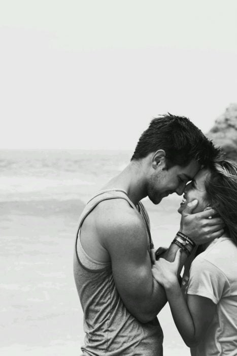 pareja de novios sonriendo después de besarse en la playa