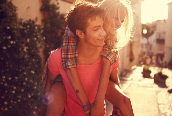 Pareja de novios caminando mientras ella la va cargando en la espalda 