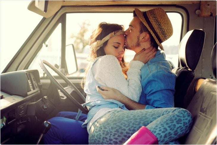 Hombre besando en la frente a una chica mientras ambos están en una camioneta 