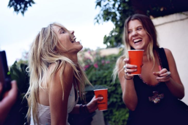 Chicas bebiendo de un vaso rojo y riendo muy contentas