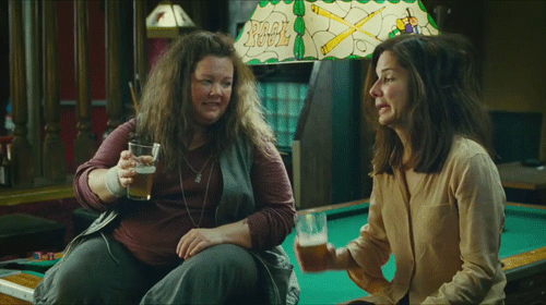 GIF sandra bullock junto a otra chica bebiendo cerveza sobre una mesa de billar 