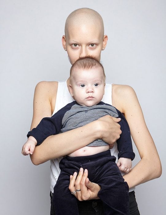 Modelo sosteniendo a su bebé en brazos mientras están en una sesión de fotos