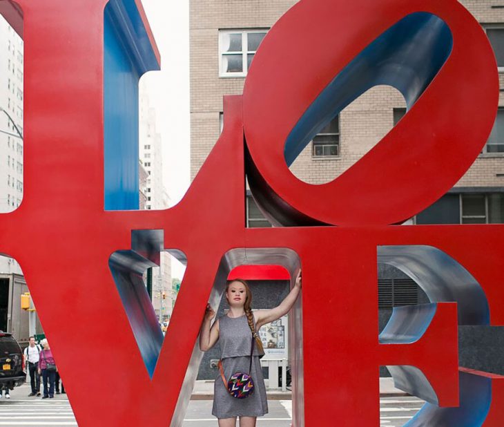 Modelo con sindrome de down parada sobre unas letras que dicen love en la ciudad de nueva york 